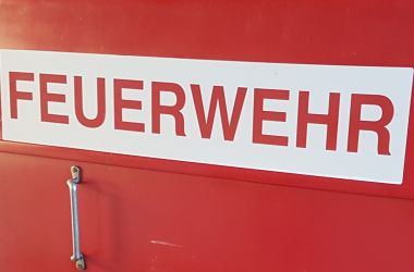 Rote Metalltür mit der Aufschrift Feuerwehr.