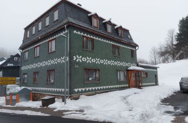 Ein dunkelgrünes Schieferhaus im Schnee.