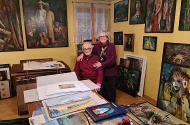 Ein Mann und eine Frau in einem Raum, umgeben von vielen Gemälden.
