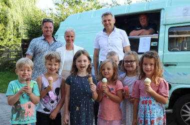 Kinder und Erwachsene stehen vor einem Eisauto.