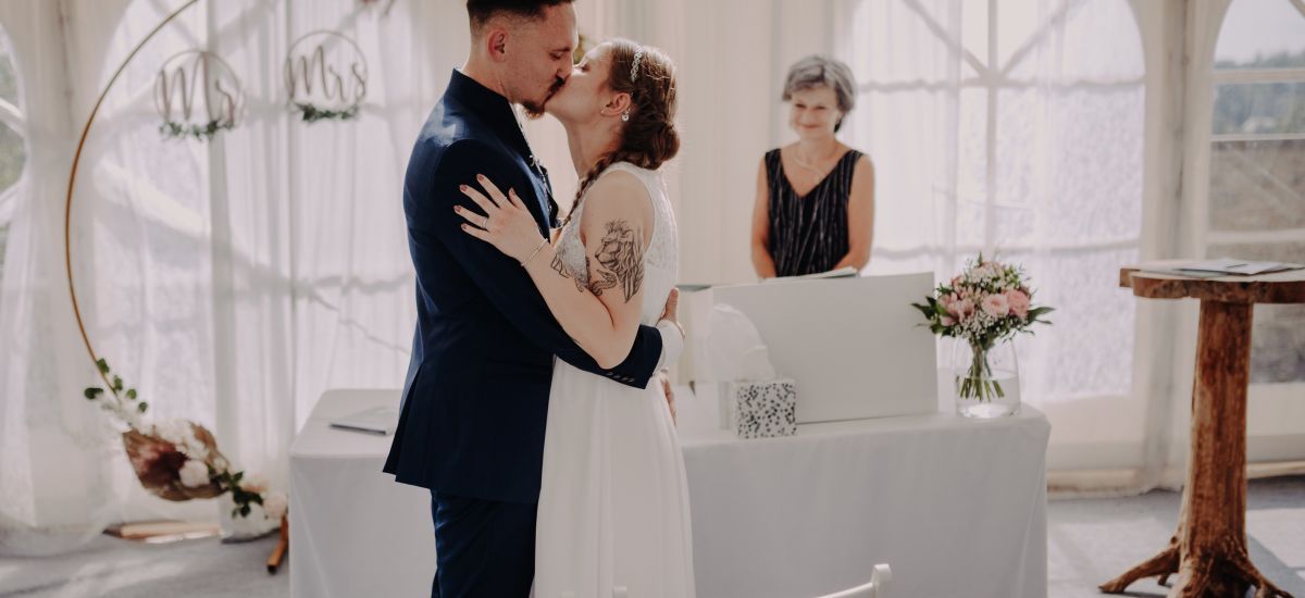 Ein junges Brautpaar küsst sich vor dem Traualtar.