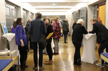 Mehrere Menschen stehen in einem Flur und unterhalten sich.