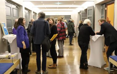 Mehrere Menschen stehen in einem Flur und unterhalten sich.