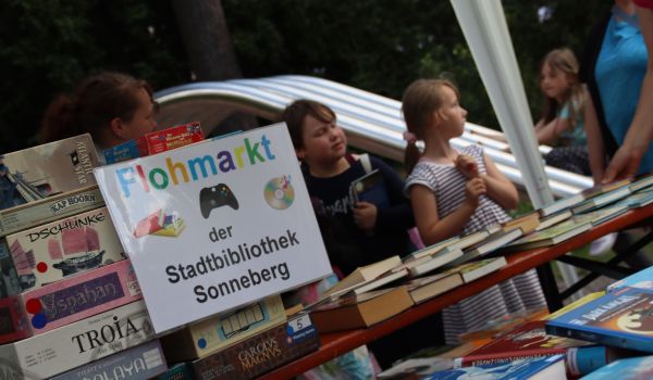 Auf einem Tisch liegen viele Bücher. Auf einem Schild steht: Flohmarkt der Stadtbibliothek Sonneberg.