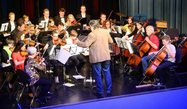 Ein Orchester sitzt auf einer Bühne und spielt.