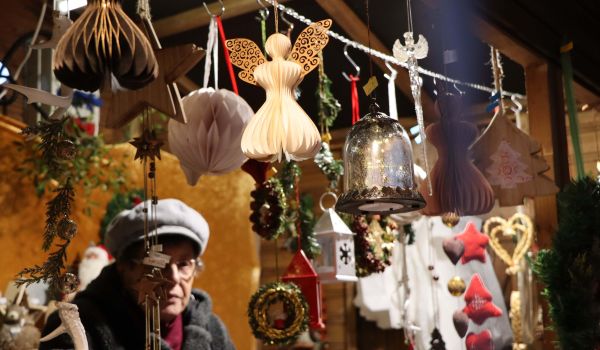 An einem Verkaufsstand hängen kleine Laternen, Engel aus Papier und andere Weihnachtsdeko an einer Leine.