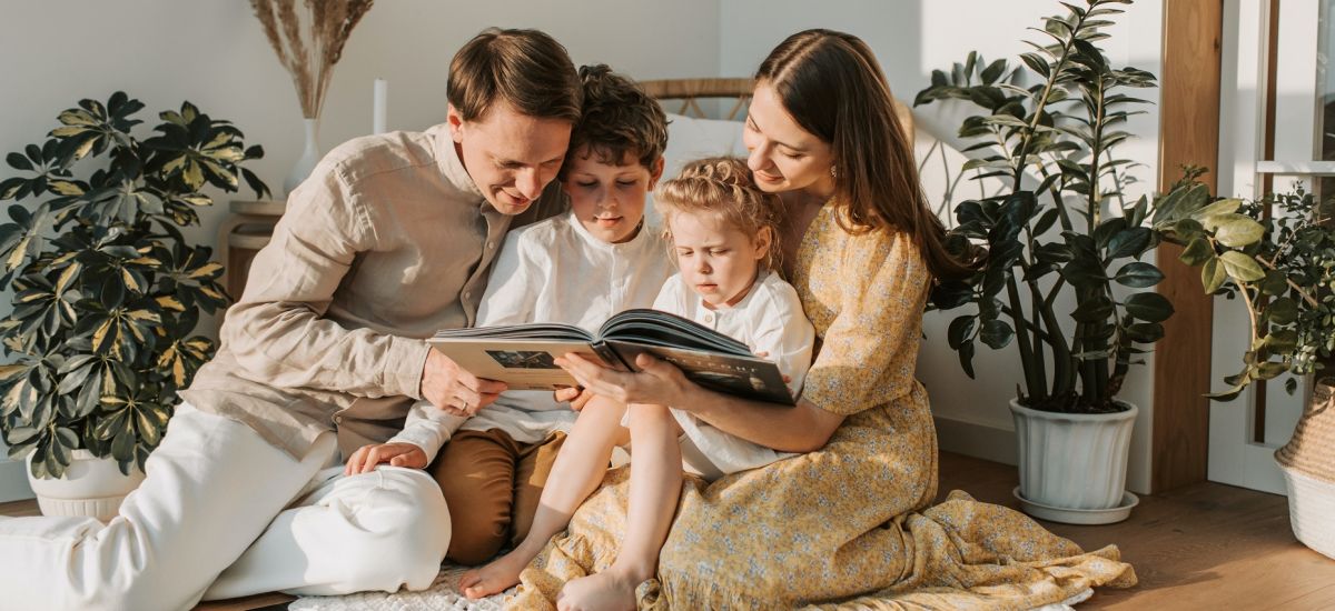 Eltern betrachten mit ihren zwei Kindern ein Buch. Foto: Pexels: Vlada Karpovich