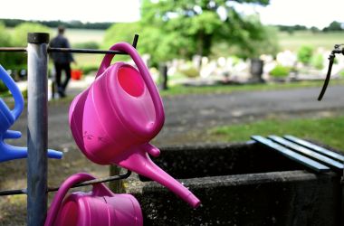 Eine Gießkanne auf einem Friedhof.