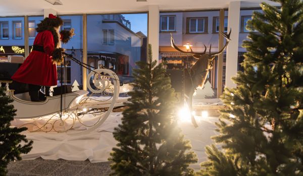Dekofigur Weihnachtsmann mit Schlitten steht in einem Schaufenster.