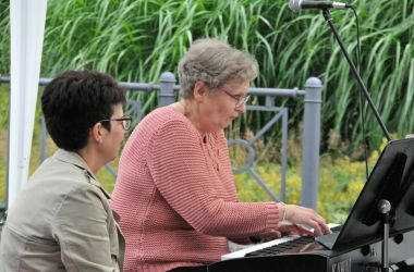 Eine Frau sitzt an einem Keyboard und spielt. Eine andere Frau sitzt daneben.