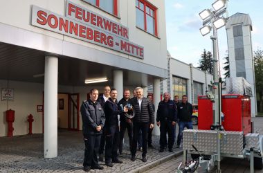 Eine Gruppe von Männern steht vor einem Feuerwehr-Gebäude.