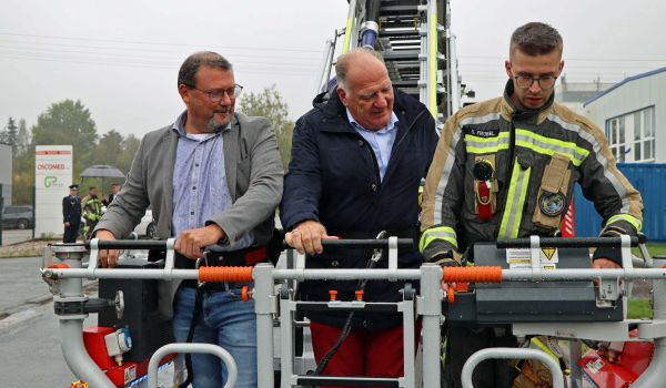 Ein Feuerwehrmann bringt zwei andere Männer im Korb der Drehleiter nach oben.