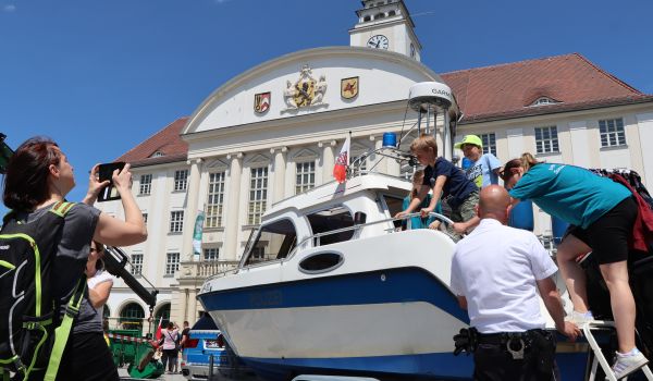 Kinder klettern über eine Leiter auf ein Polizei-Motorboot.