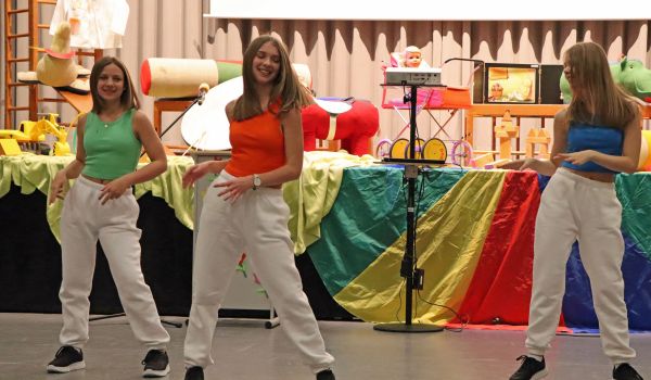 Drei Jugendliche tanzen vor einer Bühne.