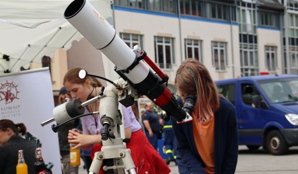 Ein Mädchen schaut durch ein Teleskop.