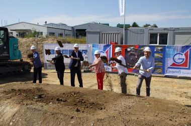Männer und eine Frau mit Spaten werfen Erde und Geröll in die Luft.