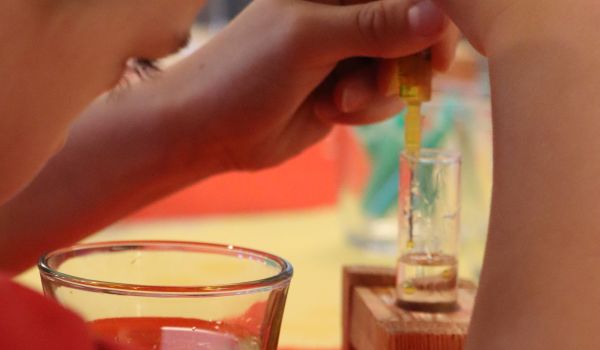 Ein Kind entnimmt Flüssigkeit mit einer Pipette.