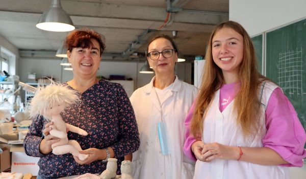 Drei Frauen stehen in einer Bastelwerkstatt nebeneinander.