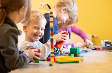 Kinder sitzen an einem Tisch und spielen.