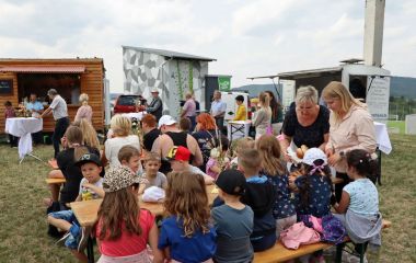 Kinder sitzen auf Bänken vor dem geplanten Freizeitareal.