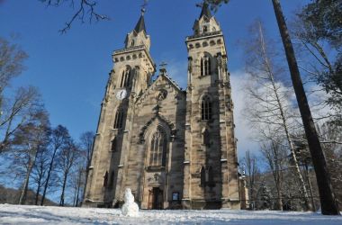 Eine Kirche umgeben von Bäumen. Es liegt Schnee.