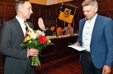 Zwei Männer stehen nebeneinander im Rathaussaal. Links: Christian Dressel hält einen Blumenstrauß.