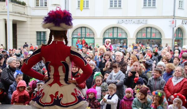 Ein Tanzmariechen auf einer Bühne vor großem Publikum.