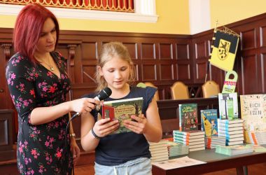 Ein Kind steht neben einer Frau und ließt die vor.