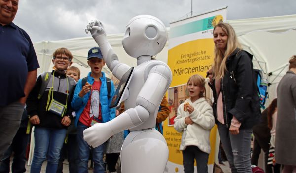 Kinder und Erwachsene stehen um einen Roboter herum.