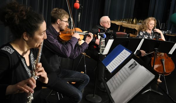Vier Personen sitzen auf einer Bühne und spielen Musik.