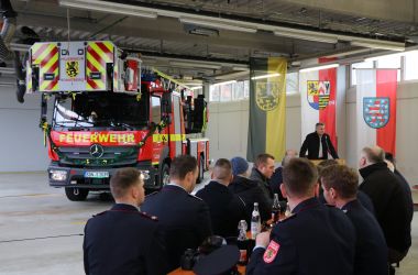 Männer in Feuerwehruniform sitzen vor einem Feuerwehrauto.