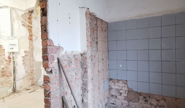 Eine Baustelle in einem Gebäude. An einer Wand wurden Fließen entfernt.