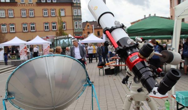 Ein Teleskop steht in der Innenstadt. Im unscharfen Hintergrund sind viele Menschen.