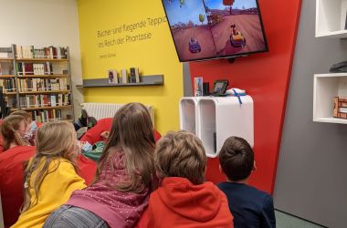 Kinder schauen auf einen Bildschirm mit Videospielen.