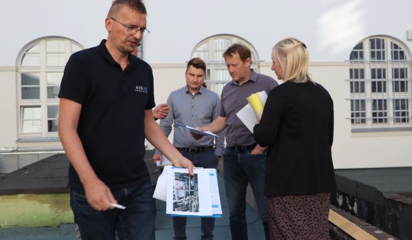 Vier Personen haben Bauunterlagen in den Händen und untehalten sich.