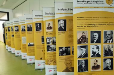 Verschiedene Roll-up Aufsteller stehen hintereinader in einer Reihe. Sie zeigen Bilder und Texte zu historischen Personen.