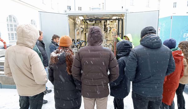 Interessierte Gäste schauen sich eine technische Anlage in einem Container an.