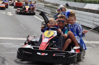 Menschen fahren in Kartautos über eine Rennstrecke.