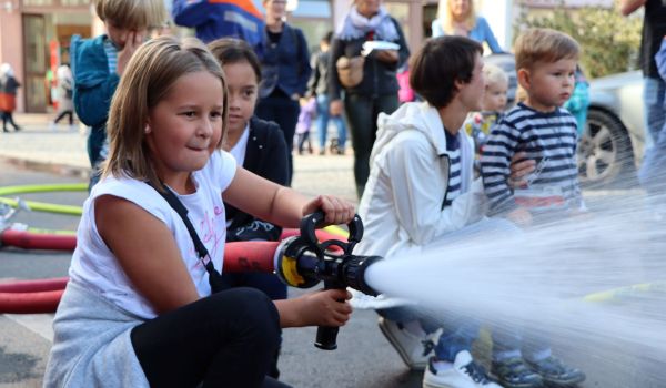 Ein Kind hält einen Feuerwehrschlauch in den Händen.