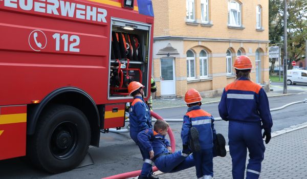 Kinder tragen einen Jungen während eines Übungseinsatzes der Feuerwehr.