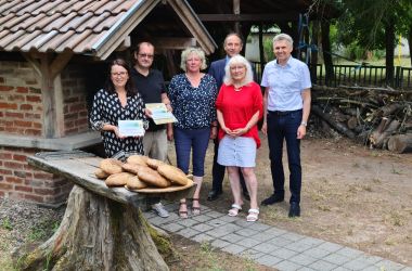 Eine Gruppe von Personen steht vor einem gemäuerten Holzbackofen.