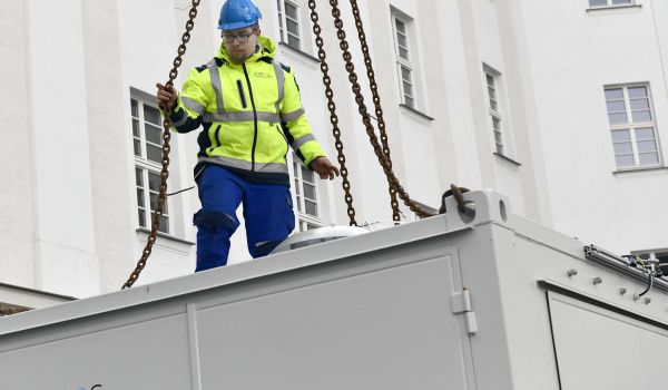 Ein Mann in gelber Warnjacke steht auf einem weißen Container.
