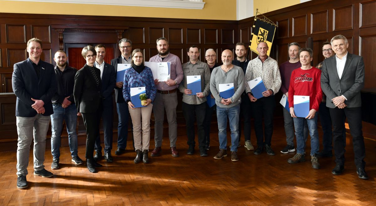 Eine Gruppe von Menschen hält ein Zertifikat in den Händen.