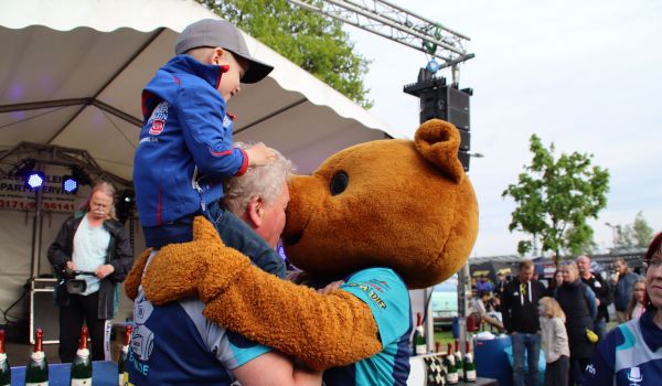 Ein Bären-Maskottchen umarmt einen Teilnehmer.