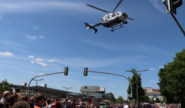Ein Polizei-Hubschrauber fliegt über den Menschen.