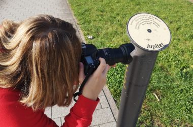 Eine Frau fotografiert eine Metallstange.