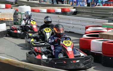 Drei Kartfahrer fahren auf der Rennstrecke.