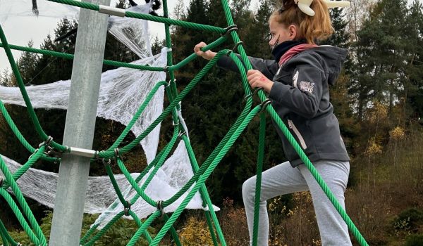 Ein Mädchen klettert auf ein Spielgerät auf einem Spielplatz.