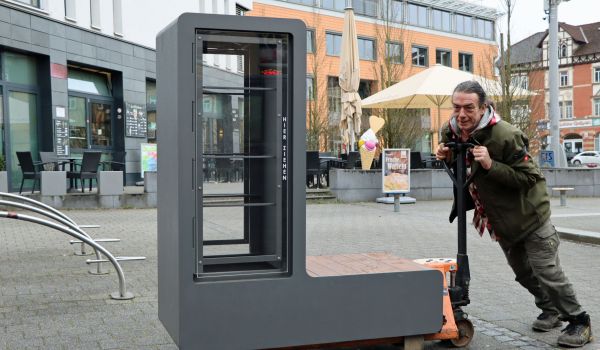 Ein Mann transportiert einen Bücherschrank auf einem Hubwagen.