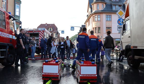 Zwei Feuerwehrautos stehen in der Innenstadt. Außen herum stehen Feuerwehrmänner und Interessierte.